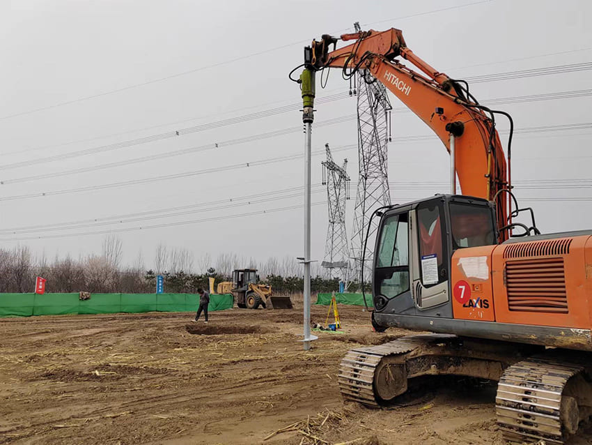 orange excavator installs a pole on a construction